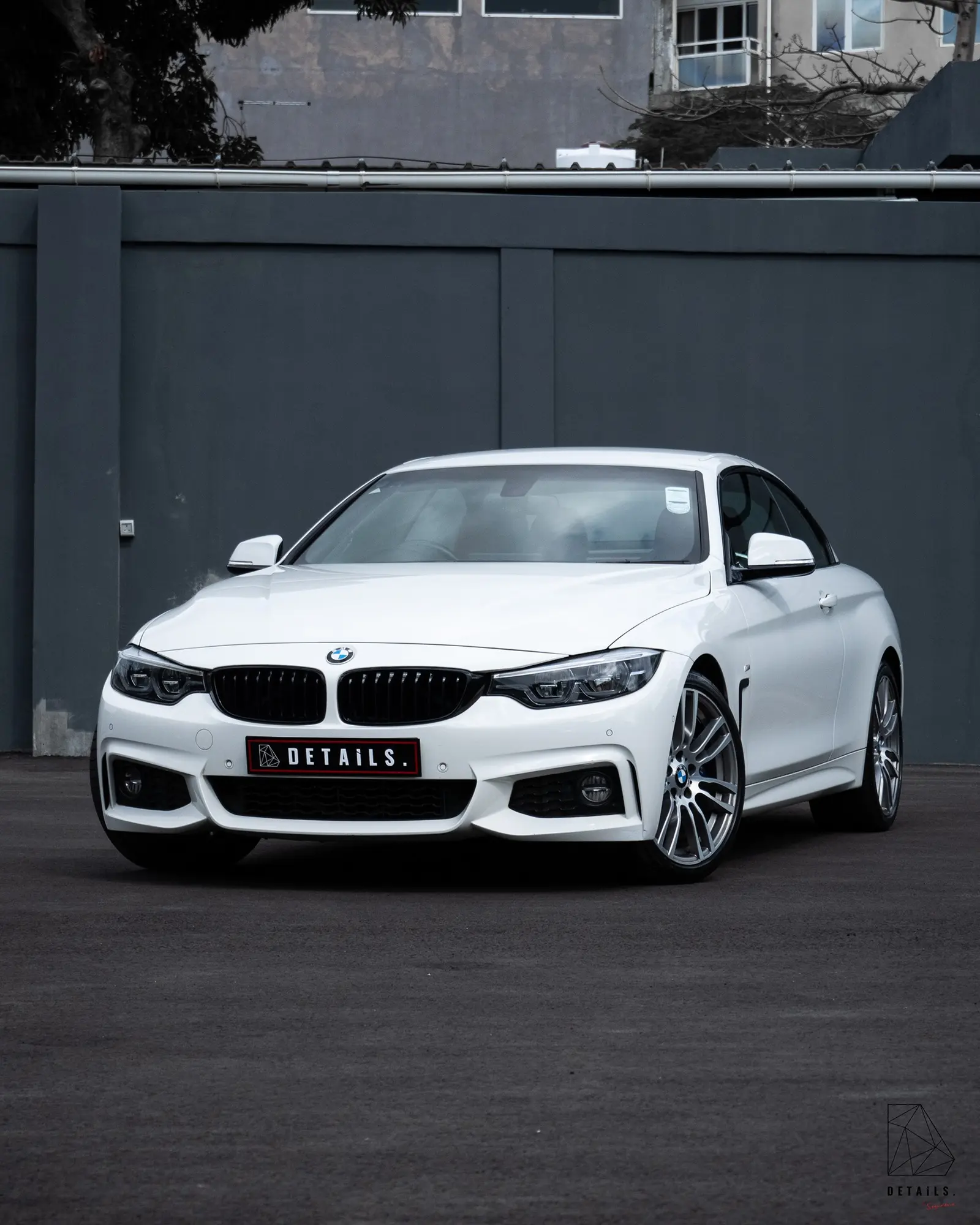 A white BMW 4 Series convertible with a DETAILS number plate