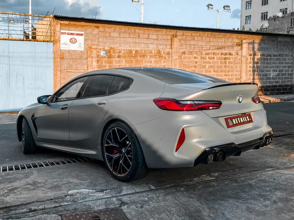 A grey BMW M8 Competition Gran Coupe seen from the rear three-quarter