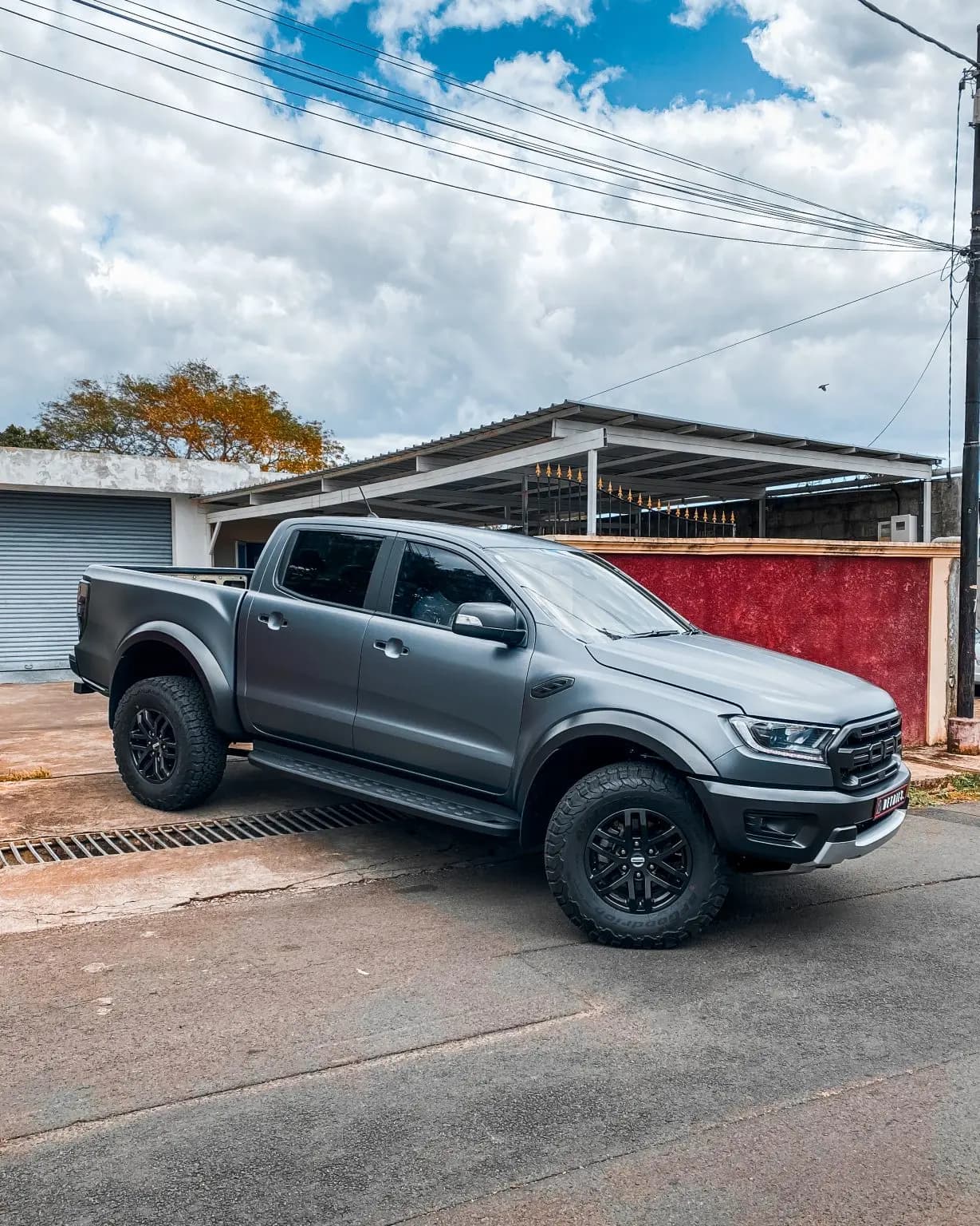 A Ford Ranger Raptor finished in matte dark grey parked outside the workshop