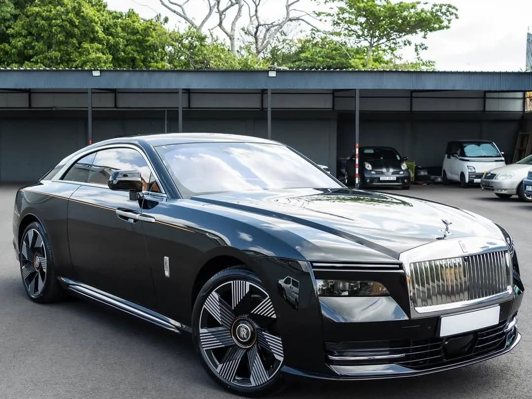 A black Rolls-Royce Spectre coupe with a two-tone finish, parked outside the workshop
