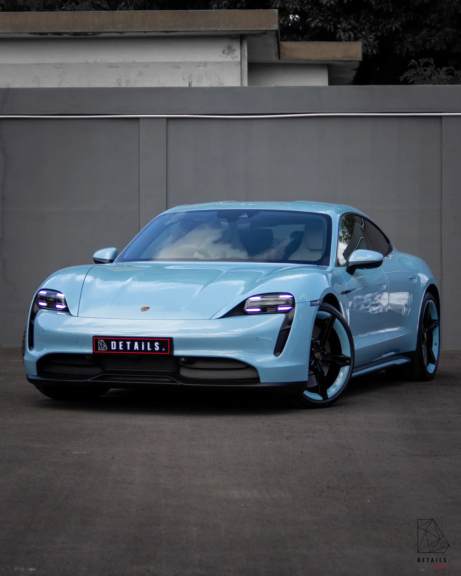 A pale blue Porsche Taycan with a DETAILS number plate