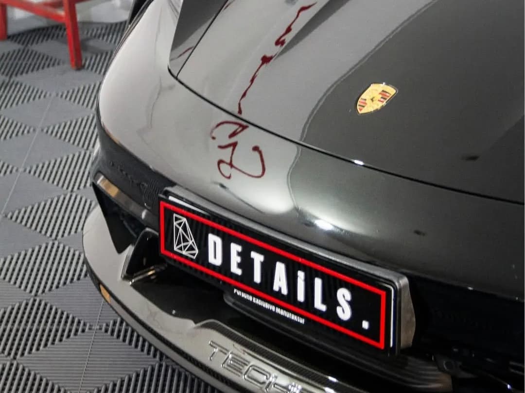 The front of a dark Porsche Taycan with a carbon fibre TECHART splitter and a DETAILS number plate
